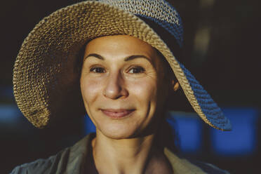 Smiling woman wearing hat with sunlight on face - IEF00098