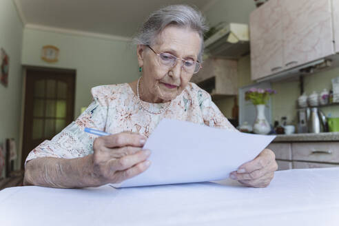 Ältere Frau mit Brille liest Papierdokument zu Hause - OSF00955