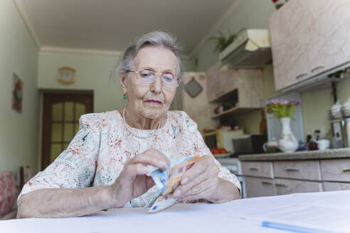 Senior woman counting money over home ownership paper - OSF00966