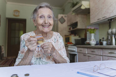 Glückliche Seniorin mit Sparguthaben zu Hause - OSF00970