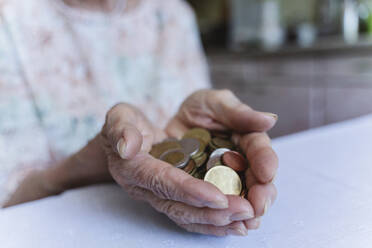 Ältere Frau hält Münzen über dem Tisch zu Hause - OSF00971