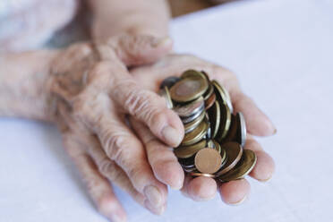 Wrinkled hands of senior woman holding coins - OSF00976