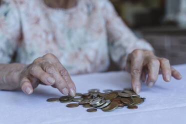 Senior woman counting coins on table at home - OSF00977