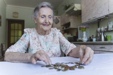 Lächelnde ältere Frau, die zu Hause Münzen zählt - OSF00979