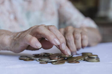 Hands of senior woman counting coins at home - OSF00980