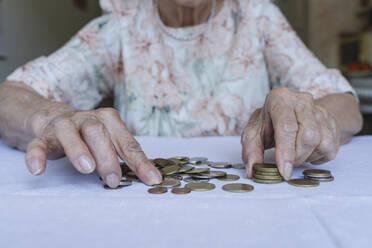 Senior woman stacking coins on table at home - OSF00981