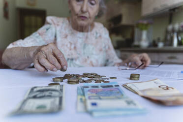 Ältere Frau beim Zählen von Münzen auf dem Tisch zu Hause - OSF00985