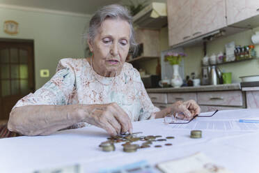 Ältere Frau zählt ihre Ersparnisse und erledigt Papierkram zu Hause - OSF00987