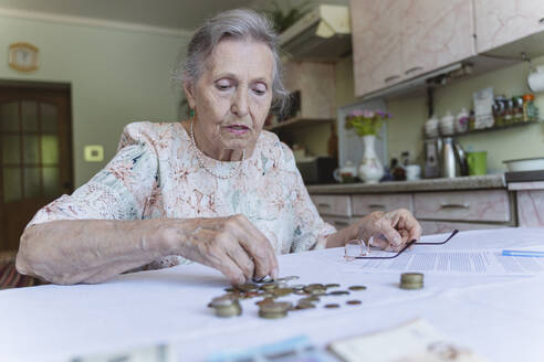 Ältere Frau zählt ihre Ersparnisse und erledigt Papierkram zu Hause - OSF00987