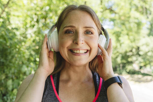 Smiling woman listening to music through headphones - OSF01000