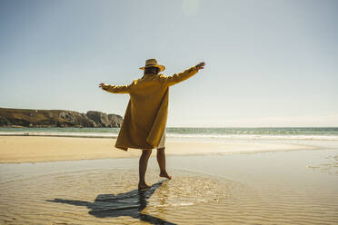 Mature woman with arms outstretched enjoying vacations at beach - UUF27304