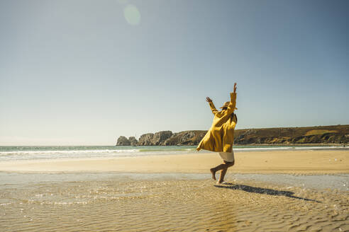 Mature woman with arms raised having fun at beach on sunny day - UUF27308