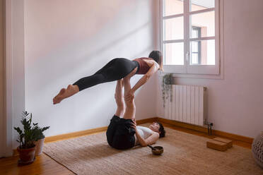 Lying on yoga mat young woman holding muscular man on lifting legs on  lesson in training room stock photo