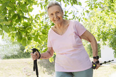 Aktive ältere Frau, die mit einem Gehstock im Park trainiert - OSF01019
