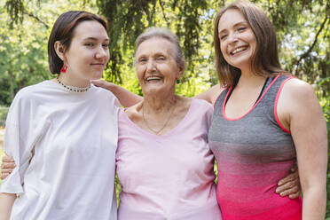 Happy senior woman with daughter and granddaughter standing at park - OSF01055