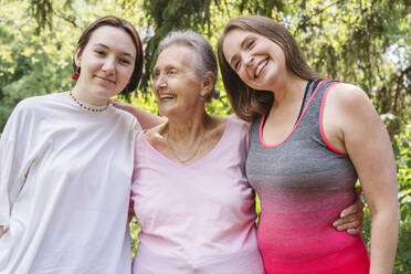 Active senior woman with daughter and granddaughter standing at park - OSF01057