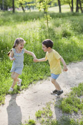 Cheerful cute girl playing with brother at park - ONAF00118