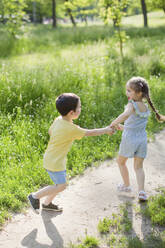 Happy siblings playing together at park on sunny day - ONAF00119