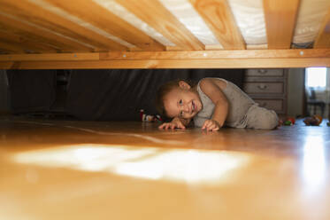 Happy boy looking under bed at home - ANAF00015
