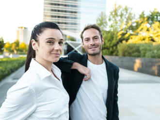 Smiling businesswoman with colleague standing at office park - AMRF00071