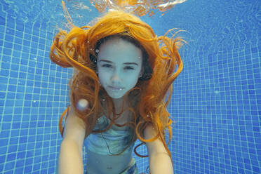 Rothaariges Mädchen in Badekleidung schwimmt unter Wasser - MEGF00129