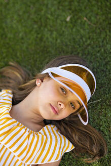 Mädchen mit braunem Haar und Sonnenblende im Gras liegend - MEGF00141