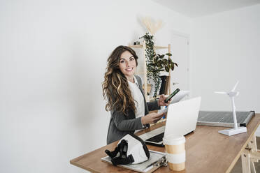 Junge Ingenieurin arbeitet in einem modernen Büro und sitzt am Schreibtisch - EBBF06496