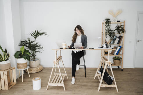 Junge Ingenieurin arbeitet in einem modernen Büro und sitzt am Schreibtisch - EBBF06497