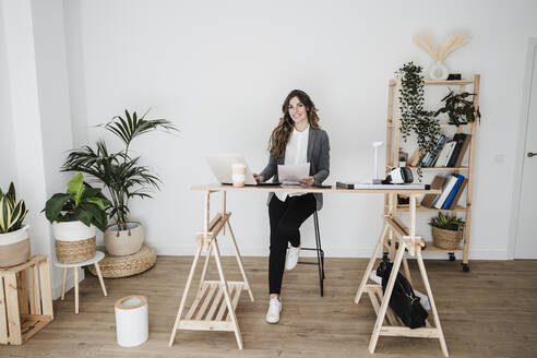 Junge Ingenieurin arbeitet in einem modernen Büro und sitzt am Schreibtisch - EBBF06498