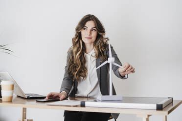 Ingenieurin arbeitet in einem modernen Büro und hält ein Windturbinenmodell - EBBF06511