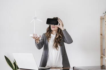 Businesswoman looking at windturbine model through vitrual reality simulator - EBBF06548