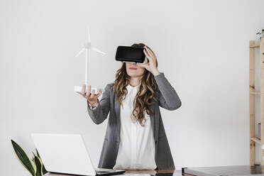 Geschäftsfrau betrachtet Windturbinenmodell im Virtual-Reality-Simulator - EBBF06548