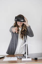 Gesturing young businesswoman using virtual reality simultor in office - EBBF06553