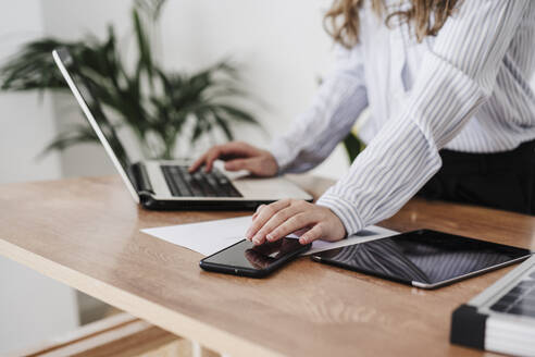 Young businesswoman working in modern office using laptop and smartphone. close up - EBBF06572