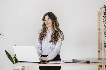 Junge Geschäftsfrau arbeitet in einem modernen Büro mit Laptop - EBBF06574