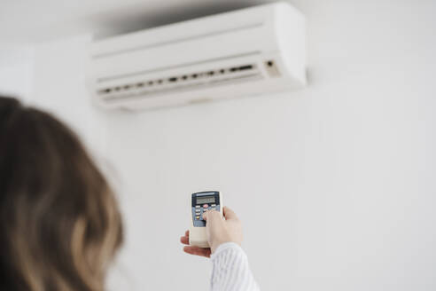 Geschäftsfrau beim Einschalten der Klimaanlage im Büro - EBBF06581