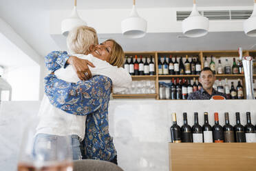 Glückliche reife Geschäftsfrau, die ihren Freund im Restaurant umarmt - DCRF01546