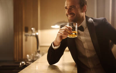 Handsome young man having a glass of whiskey at night club. Man at nightclub having drink at a bar counter. - JLPPF00003