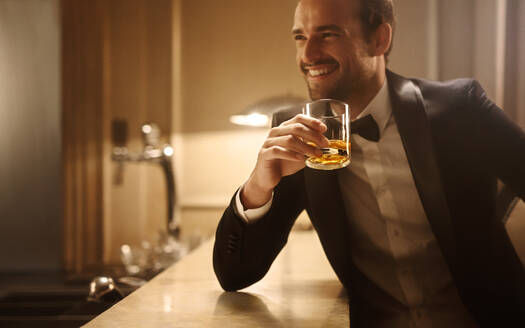Gutaussehender junger Mann mit einem Glas Whiskey im Nachtclub. Mann im Nachtclub mit einem Drink an der Theke. - JLPPF00003