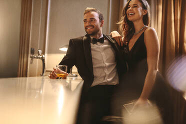 Beautiful couple enjoying weekend at a pub. Man and woman in formalwear standing at a bar counter in the night club. - JLPPF00008