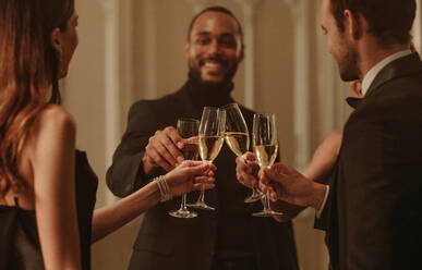 Group of friends celebrating with champagne at a nightclub. Multi-ethnic group of men and women toasting champagne glasses at a party. - JLPPF00025
