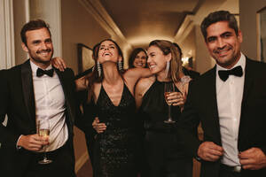 Group of men and women walking in corridor with drinks. Multi-ethnic group of people at a gala night. - JLPPF00060