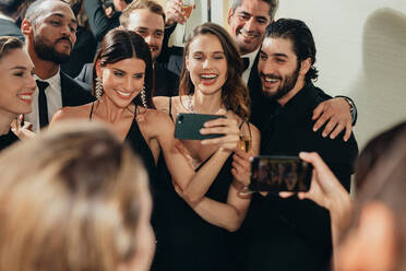 Schöne Frau, die Selfies mit seinen Freunden auf einer Party macht. Diverse Gruppe von Freunden, die ein Selfie auf einer Galanacht machen. - JLPPF00066