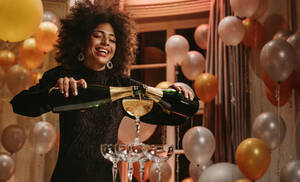 Schöne Frau gießt zwei Flaschen Champagner in Gläser Turm auf Gala-Nacht-Party. Lächelnde Frau im Abendkleid Füllung Pyramide von Gläsern mit Champagner. - JLPPF00076