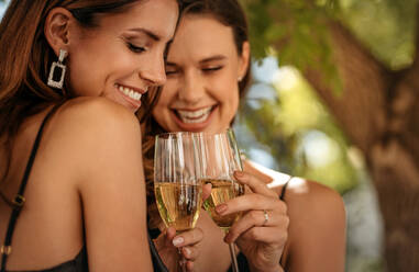 Beste Freundinnen stoßen auf einer Party mit Sektgläsern an. Frauen feiern auf einer Veranstaltung mit Wein. - JLPPF00096