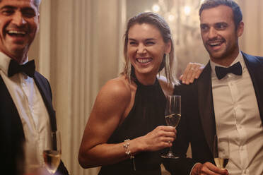 Beautiful woman smiling with friends at a party. Group of socialites with champagne at a gala night. - JLPPF00103