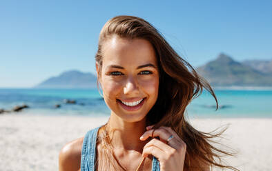 Close up Porträt der schönen jungen Frau am Strand. Junge kaukasische weibliche Modell am Meer Blick auf die Kamera und lächelnd. - JLPPF00122