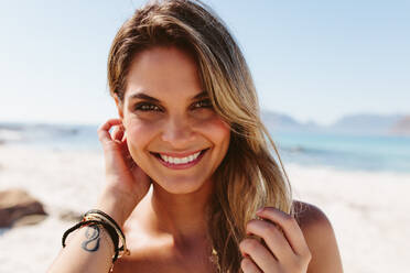 Close up portrait of beautiful young woman smiling on the beach. Charming young caucasian female model looking at camera. - JLPPF00126