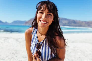 Close up portrait of woman on the beach with beautiful smile. Young caucasian female model on the seashore looking away and smiling. - JLPPF00131