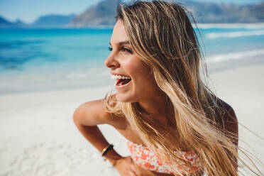 Close up portrait of attractive young woman on the beach. Caucasian female model on the seashore looking away and laughing. - JLPPF00158